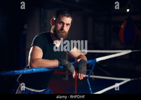 Portrait of young male boxer debout dans l'anneau dans le club de boxe d'entraînement dur après Banque D'Images