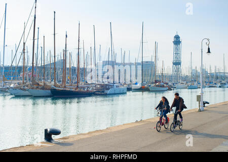 Couple riding bicycles par Barcelona marina avec des yachts, Espagne Banque D'Images