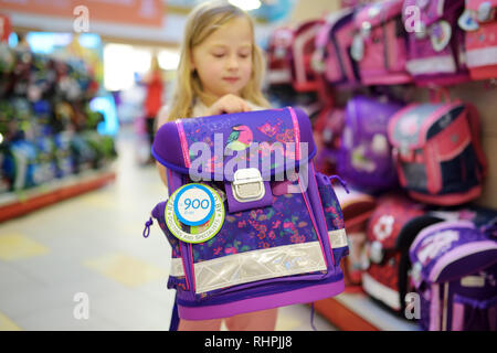 Cute little girl le choix d'un sac avant de commencer les cours. Adorable sac à dos pour l'école de l'élève l'achat dans un magasin. Concept Retour à l'école. Banque D'Images