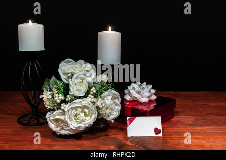 Magnifique bouquet de fleurs bougies blanches disposées sur un support avec un cadeau et une carte sur une table en bois. La fête des mères, Pâques, Saint-Valentin, anniversaire Banque D'Images