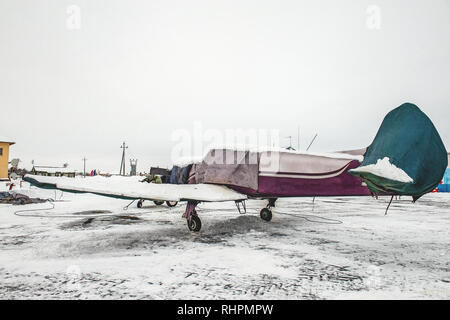 Un petit avion s'élève dans un cas, le protégeant des précipitations à l'aéroport à l'aéroport dans l'hiver Banque D'Images