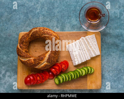 Un petit-déjeuner turc typique de simit, tomates, concombre et fromage, avec du thé turc, servi dans un verre. Banque D'Images