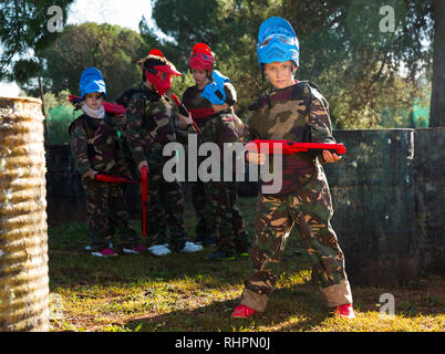 Preteen boy en uniforme et la tenue prête pour pistolet à jouer avec des amis en plein air paintball Banque D'Images