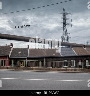 Maisons de la rue dominé par les tuyaux d'alimentation de gaz industriels dans la Rue du Châtelet à Charleroi, Belgique Banque D'Images