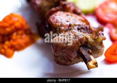 Très savoureux morceaux de viande sont plantées sur une brochette et frits sur un feu ouvert. La viande se trouve sur une plaque blanche et sera servi à la table de tomat Banque D'Images