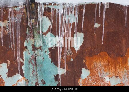 La paroi métallique de l'ombre bleue est rouillé avec le temps et les conditions météorologiques. C'est l'hiver à l'extérieur et de glaçons pendent du toit. Banque D'Images