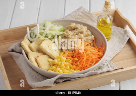 Bol Bouddha avec quinoa, tofu frit, endives, carottes, maïs, et l'huile d'olive Banque D'Images