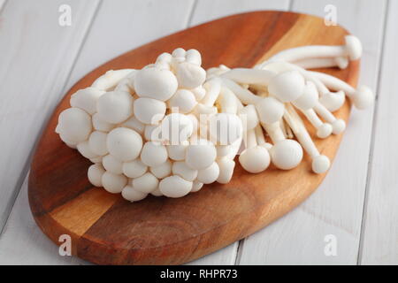 Bouquet de champignons shimeji brut également connu sous le nom de champignons en hêtre blanc sur une planche à découper en bois Banque D'Images