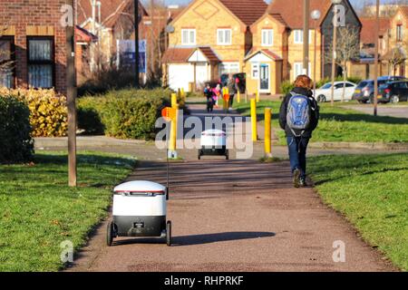 Les piétons passer au sujet de leur vie quotidienne en tant que technologies Starship robots autonomes faire les livraisons d'épicerie de routine autour de Milton Keynes. Banque D'Images