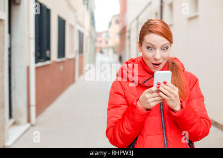 Surpris woman receiving nouvelle choquante sur un téléphone intelligent sur la str Banque D'Images
