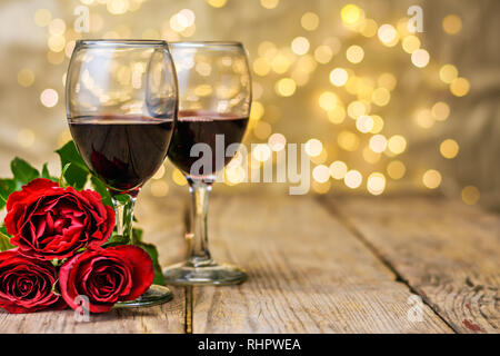 Valentine's Day still life. Deux verres de vin et de roses rouges sur une table rustique en bois devant un arrière-plan lumineux brouillée avec copie espace pour t Banque D'Images