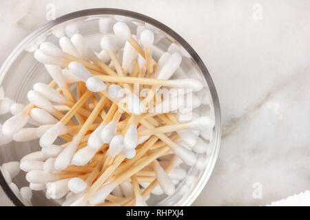 Un passage photo gros plan de bambou coton-tiges dans un bocal de verre sur une surface en marbre avec copyspace Banque D'Images