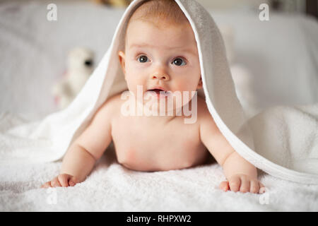 Baby Girl se cache sous la couverture blanche. Banque D'Images