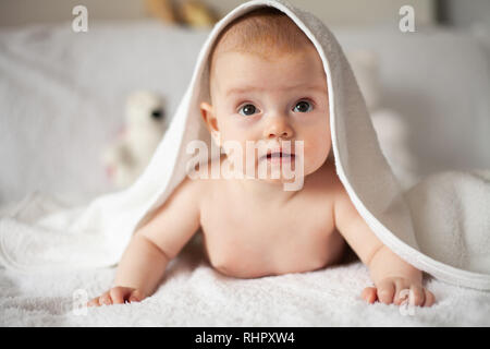 Baby Girl se cache sous la couverture blanche. Banque D'Images