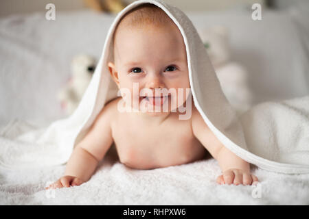 Baby Girl se cache sous la couverture blanche. Banque D'Images