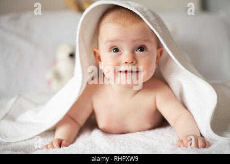 Baby Girl se cache sous la couverture blanche. Banque D'Images