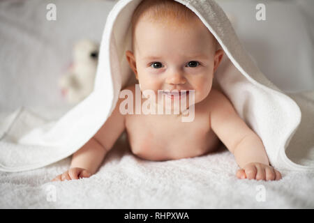 Baby Girl se cache sous la couverture blanche. Banque D'Images