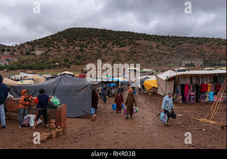 Vue d'un souk berbère bazar marché hebdomadaire tenu dans la campagne dans la boue et par mauvais temps. Une scène animée de locaux et de véhicules au Maroc Banque D'Images