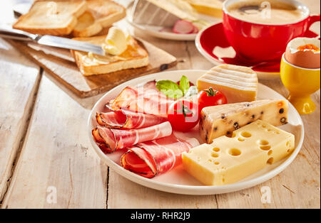 La variété de fromage et bacon servi pour sandwich sur assiette blanche, avec des tomates fraîches, toasts, œufs durs et tasse de café Banque D'Images