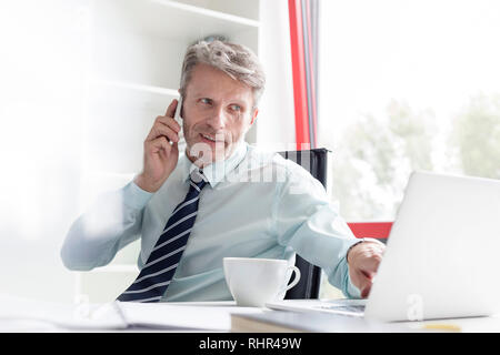 Businessman talking on phone lors de l'utilisation de office Banque D'Images