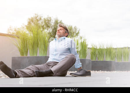 Assez mature businessman sitting on office terrace against sky Banque D'Images