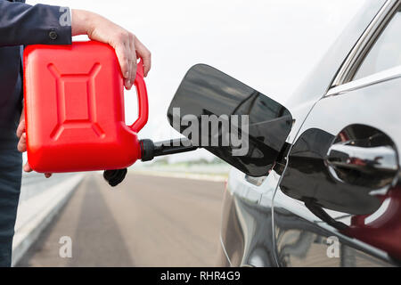 Portrait of businesswoman avec voiture de ravitaillement canister against sky Banque D'Images