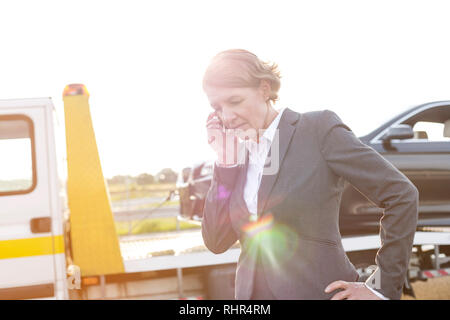 Tendu businesswoman talking on phone while dépanneuse prendre sa voiture Banque D'Images