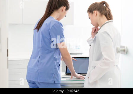 Colleagues discussing over laptop at desk in clinic Banque D'Images