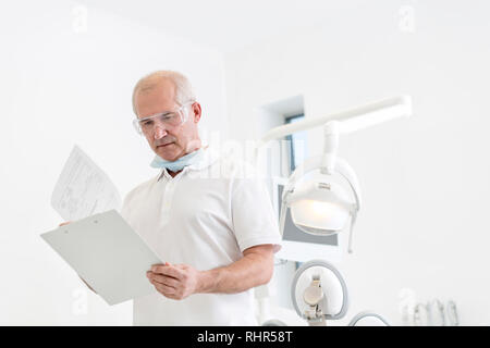 Lecture des rapports médicaux dentiste principal à une clinique dentaire Banque D'Images