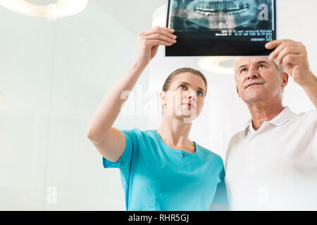 Certains hommes et femmes dentistes examining x-ray à la clinique Banque D'Images