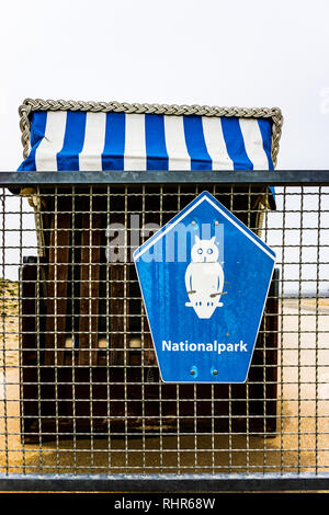 Typique du nord de l'allemand en osier chaises de plage couverte de toit pliable et protégeant du vent sur les parois d'une plate-forme en bois sur pilotis avec vue sur mer. Banque D'Images