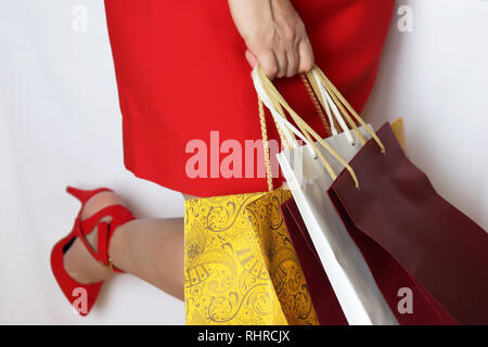 Woman with shopping bags isolé sur fond blanc. Jeune fille en robe rouge et des chaussures à talons hauts, concept de vente, d'achats et des cadeaux Banque D'Images