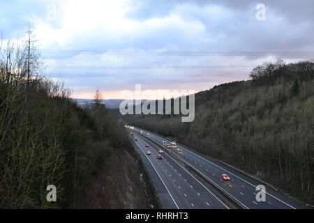 Traffic tourne librement sur les M25, entre la sortie 4-5, lorsqu'il passe par une coupe dans les North Downs près de Shoreham, Kent de pilotes en bois. Crépuscule d'hiver Banque D'Images