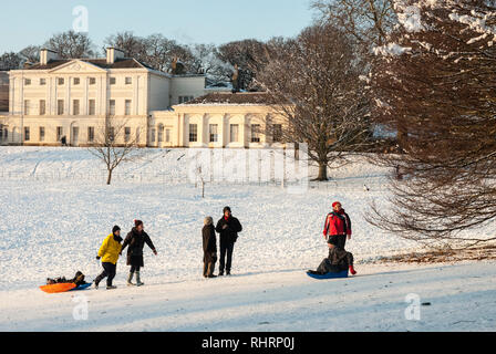 Sur un des hivers enneigés jour traîneau familles le long des pentes en face de Kenwood House, Hampstead, au Royaume-Uni. Banque D'Images