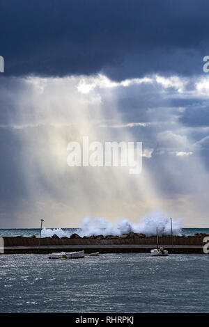 Sur la mer Méditerranée vertical avec pier contre un ciel noir avec lumière dramatique sur des éclaboussures des vagues sur un jour d'hiver à Majorque, Espagne. Banque D'Images