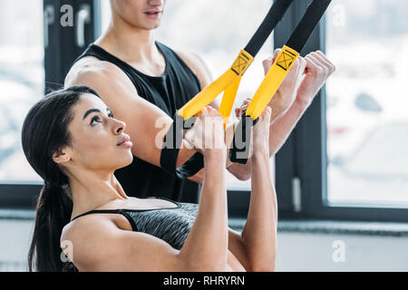 Sportive concentré african american woman exerçant avec sangles de suspension in gym Banque D'Images