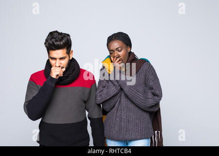 Jeune couple interracial african girl indian guy en gris pulls, écharpes ensemble isolé sur fond de mur gris. Mode de vie sain, malade malades maladie Banque D'Images