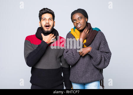 Jeune couple interracial fille africaine arabe guy en gris pulls, écharpes ensemble isolé sur fond de mur gris. Mode de vie sain, malade malades maladie Banque D'Images