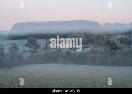 L'église St Oswald dans le brouillard d'hiver et le gel avant le lever du soleil. Widford, Cotswolds, Oxfordshire, Angleterre Banque D'Images