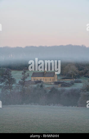 L'église St Oswald dans le brouillard d'hiver et le gel avant le lever du soleil. Widford, Cotswolds, Oxfordshire, Angleterre Banque D'Images