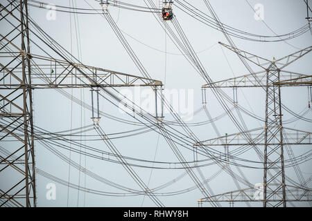 04 février 2019, en Rhénanie du Nord-Westphalie, Pulheim : Les travailleurs assemblage lignes électriques sur des colonnes d'alimentation sur un champ. Photo : Federico Gambarini/dpa Banque D'Images