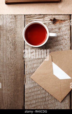 Une tasse de thé et l'enveloppe avec une lettre sur fond de bois vintage et élégant, un minimum de pause ou du thé de matin concept, vue, télévision haut lay, copy space Banque D'Images