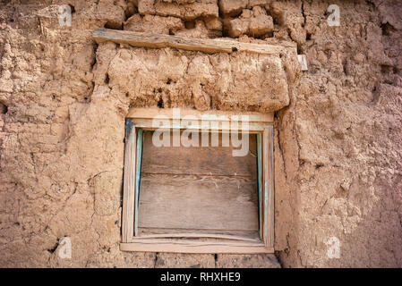 Vieux mur de maison en adobe délabré avec une fenêtre à bord à Ranchos de Taos, Nouveau-Mexique, Etats-Unis Banque D'Images