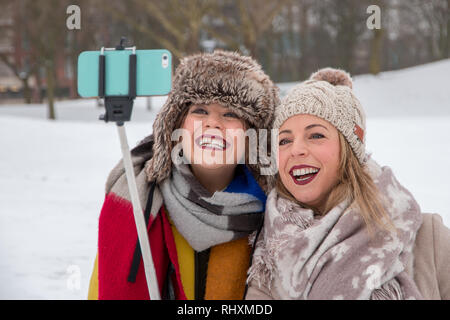 Deux femmes prenant une 'snow' selfies dans parc du château, Bristol, Royaume-Uni Banque D'Images