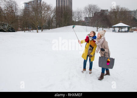 Deux femmes prenant une 'snow' selfies dans parc du château, Bristol, Royaume-Uni Banque D'Images