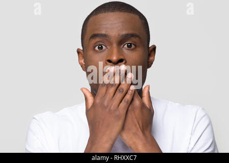 Choqué horrifié homme africain couvrant la bouche avec mains peur Banque D'Images