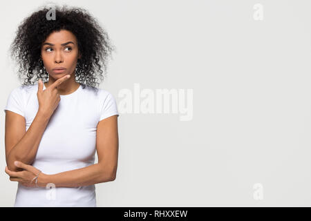 Thoughtful african woman holding hand on chin looking at copyspace Banque D'Images