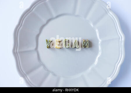 Le mot 'vegan' écrit avec pâtes vert des lettres dans un plat beige. Le véganisme, fond d'arrière-plan conceptuel. Close up Vue de dessus. Banque D'Images