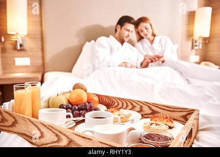 L'alimentation dans un lit. Couple hugging in a hotel room lit ensemble. Histoire d'amour. Close-up of breakfast Banque D'Images