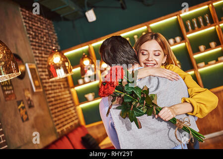 Si heureux dans l'amour. L'homme est serrant sa petite amie avec passion. Jeune blonde woman is holding buquet avec roses rouges Banque D'Images